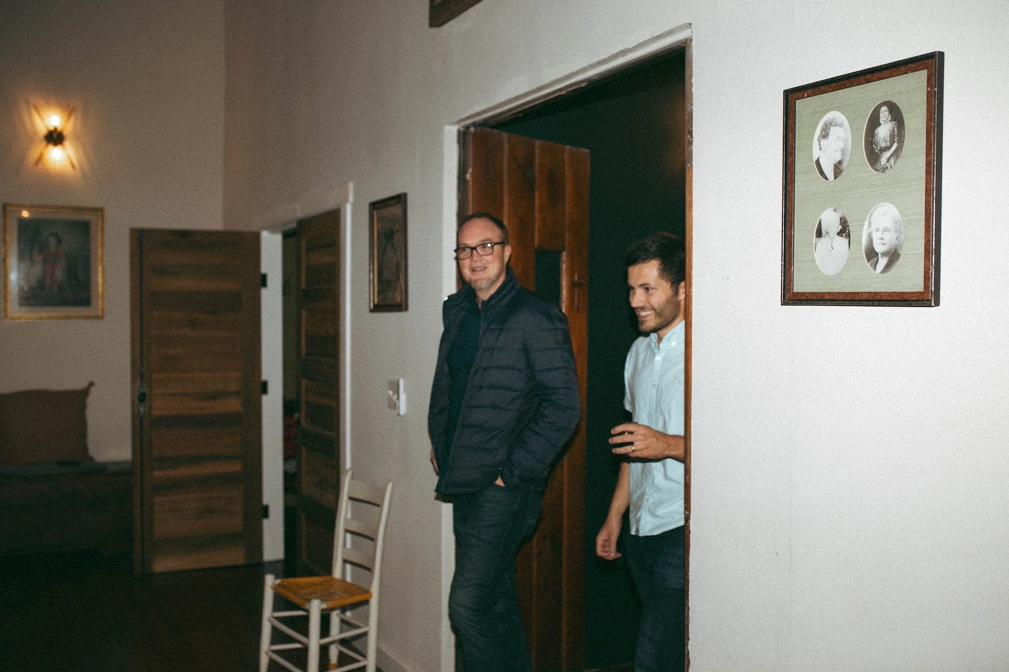 Two GWG colleagues chatting in a doorway hung with antique portraits.