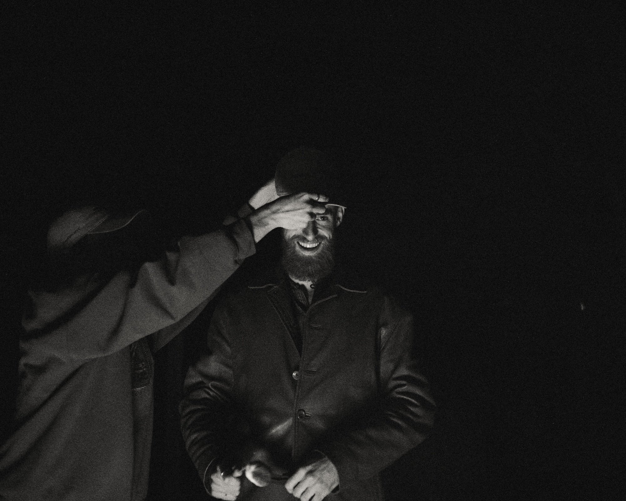 A GWG faculty member adjusts Brady Gilliam's cap near the campfire at the company retreat.