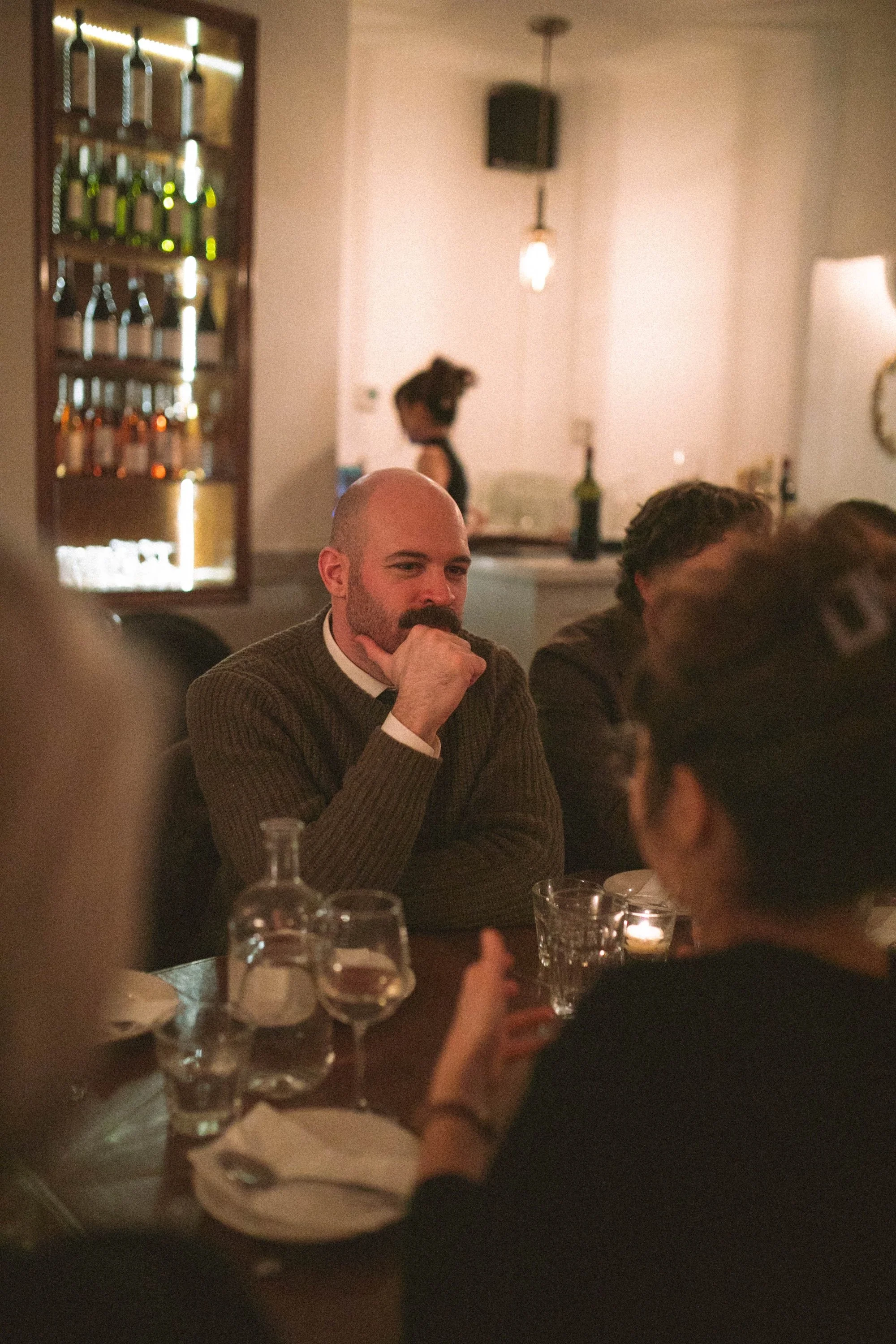 A Gilliam writing coach listening intently beside a softly lit wine display.