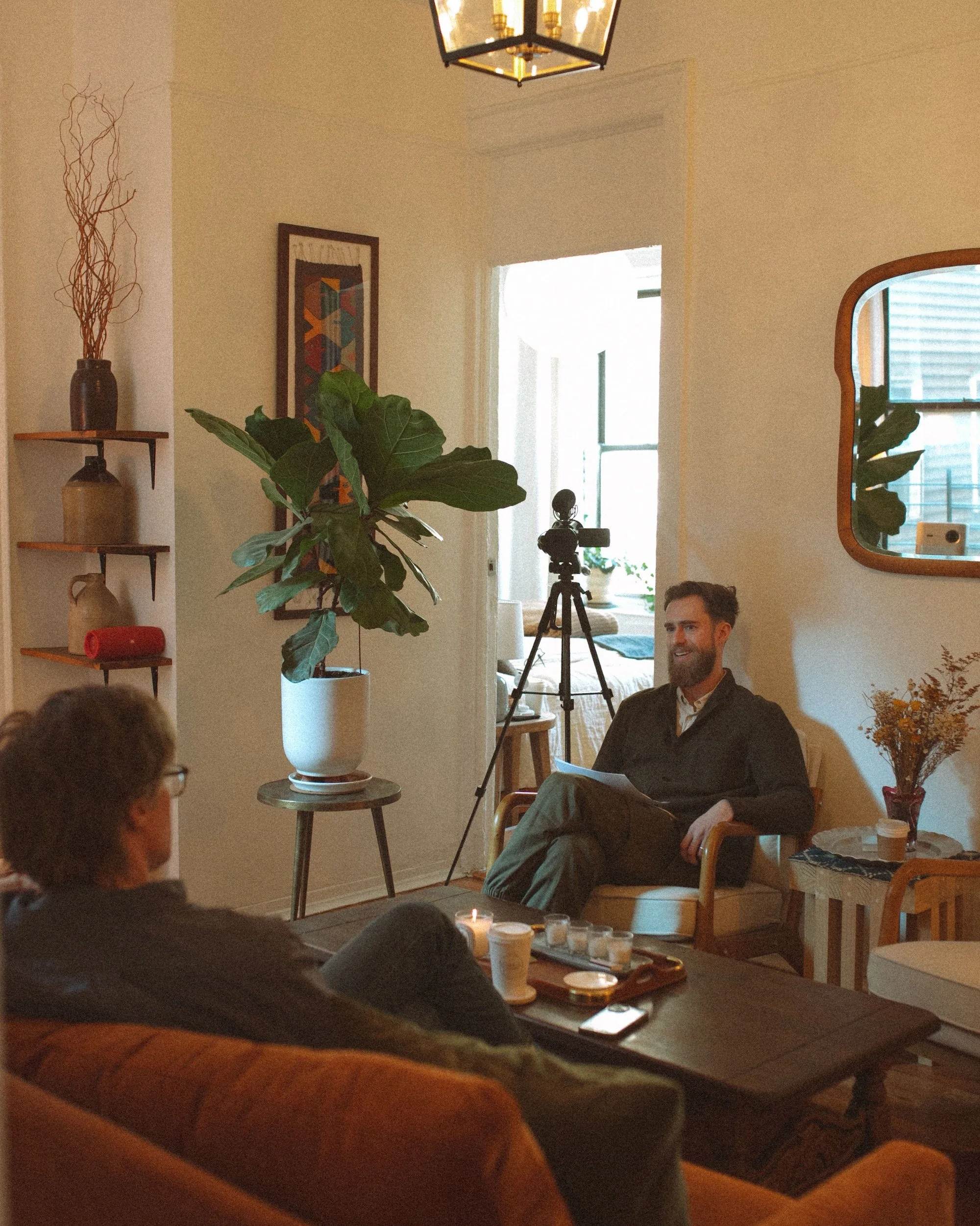 Brady Gilliam films an interview with a GWG faculty member in a plant-filled living room.