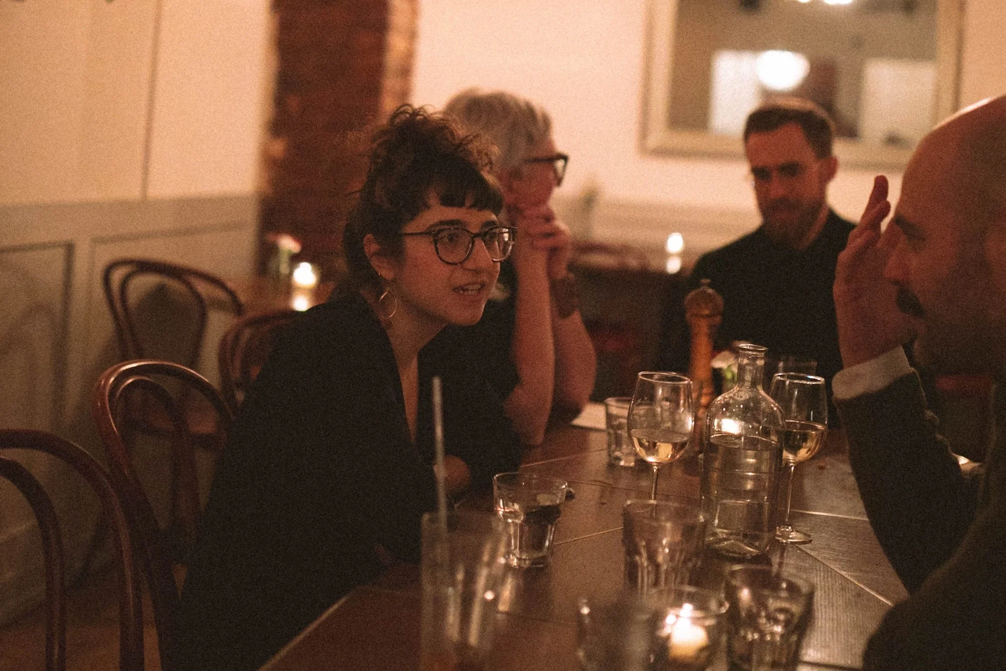 A faculty member speaking animatedly with colleagues over wine at dinner.