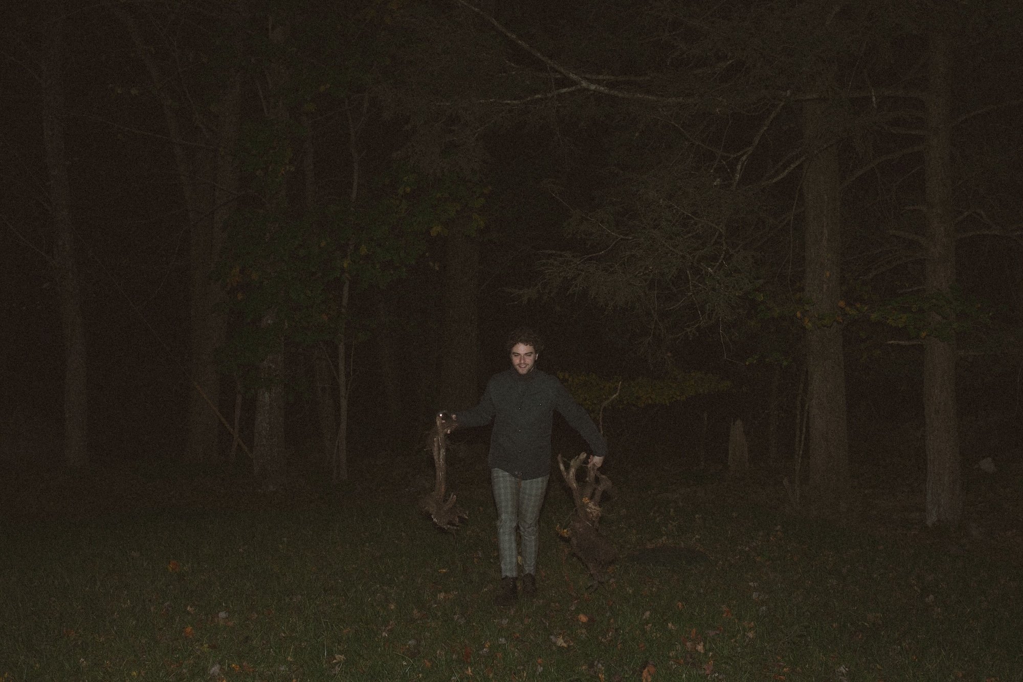 A Gilliam Writers Group faculty member carrying firewood across the dark lawn of the retreat house.