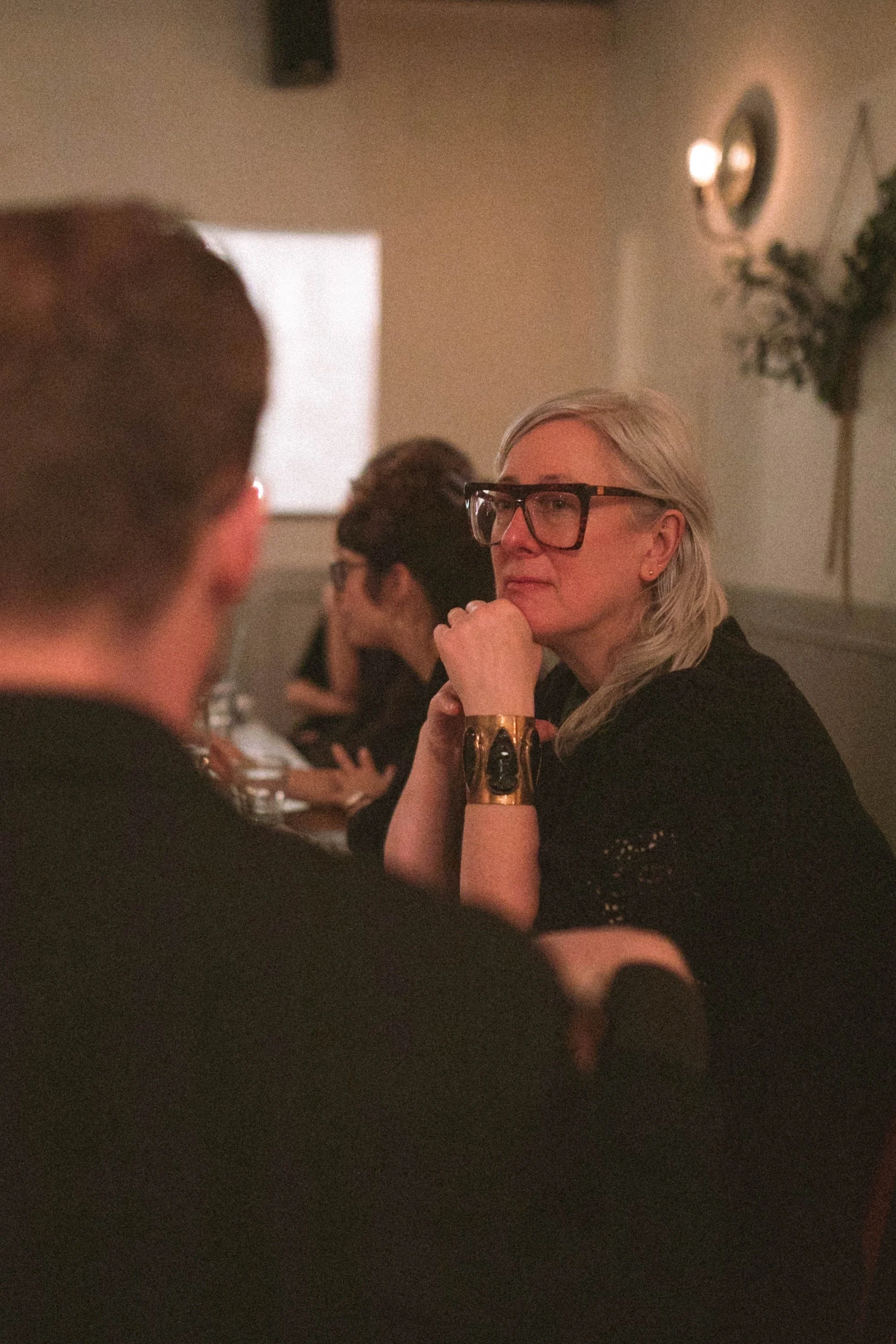 A Gilliam Writers Group faculty member listening thoughtfully during dinner conversation.