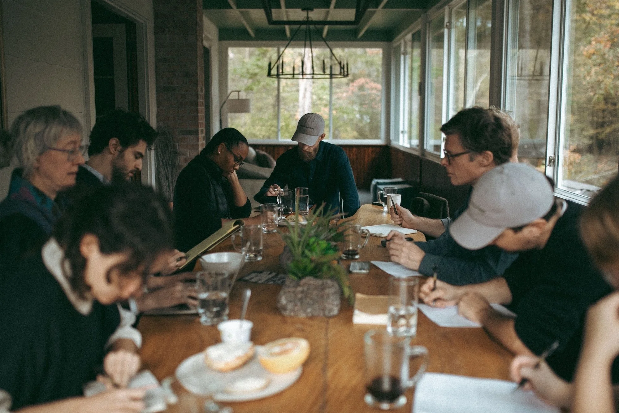 Writers taking notes during a round-table workshop overlooking the woods.
