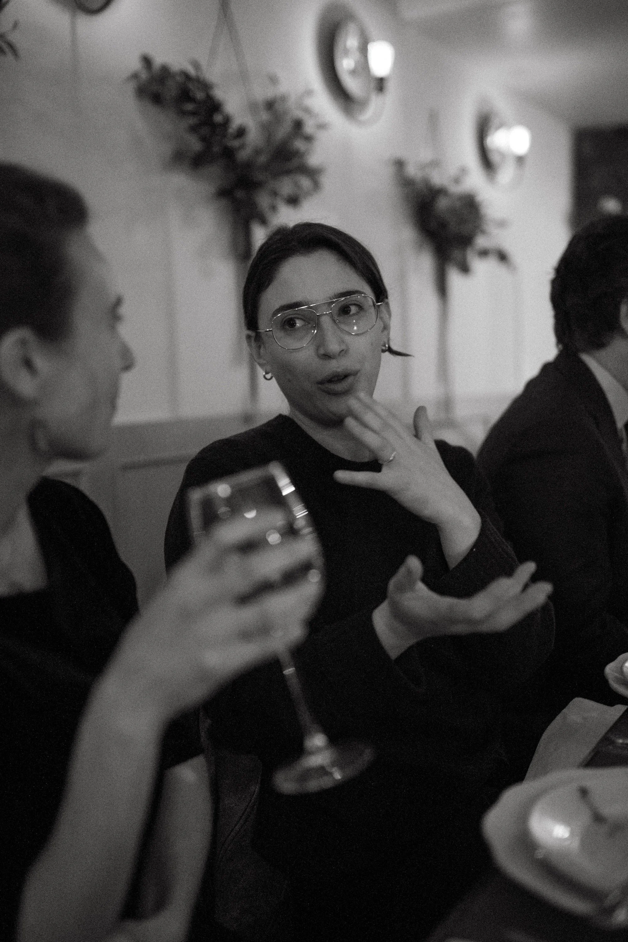 A Gilliam Writers Group faculty member gesturing mid-conversation over a glass of wine.