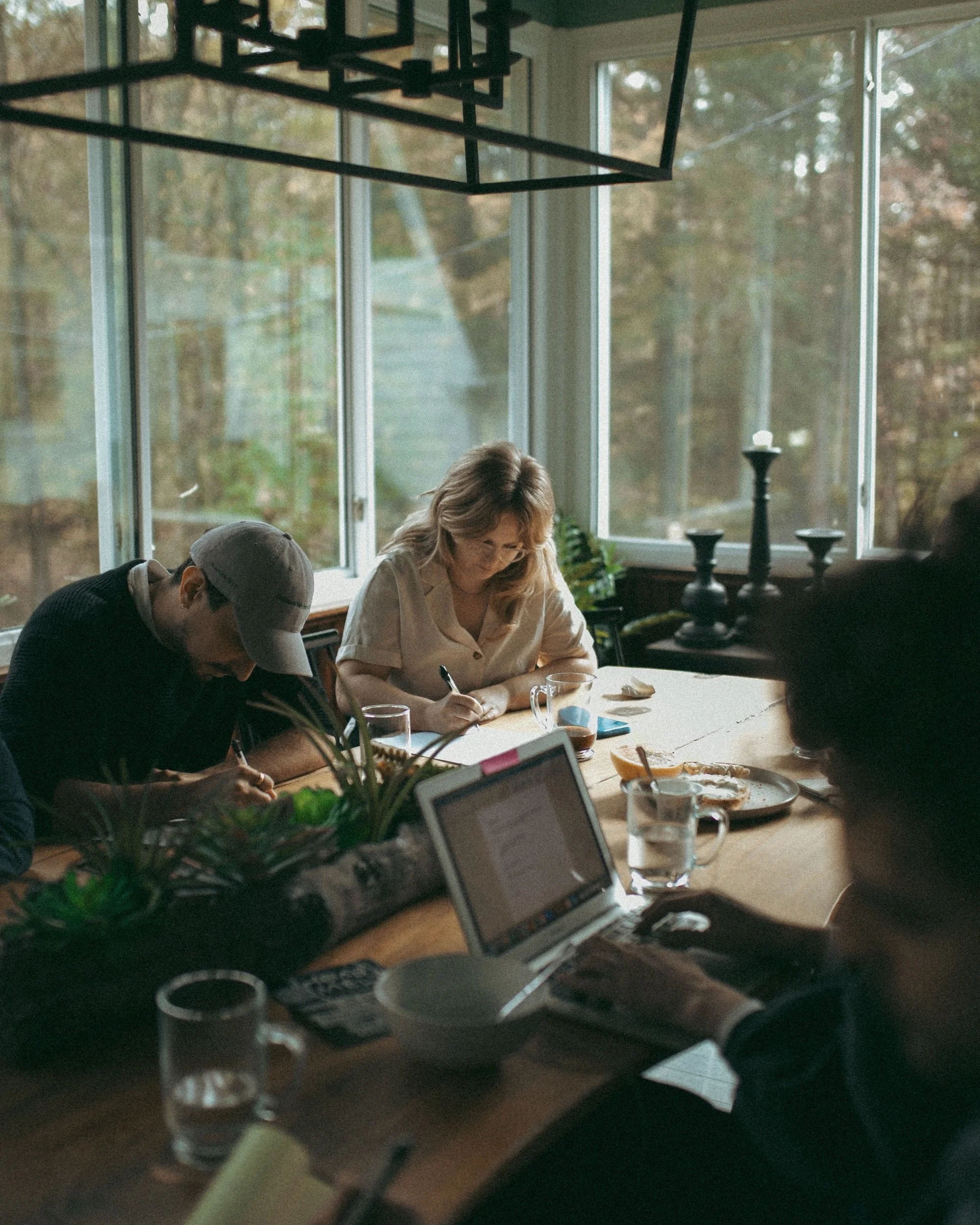 Gilliam Writers Group faculty writing at a sunlit workshop table.