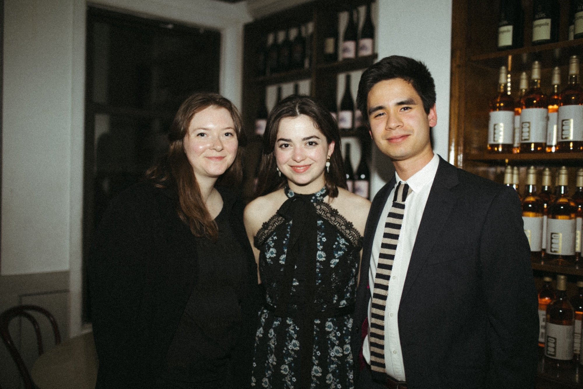 Three literary agents posing together at an intimate wine-bar dinner.