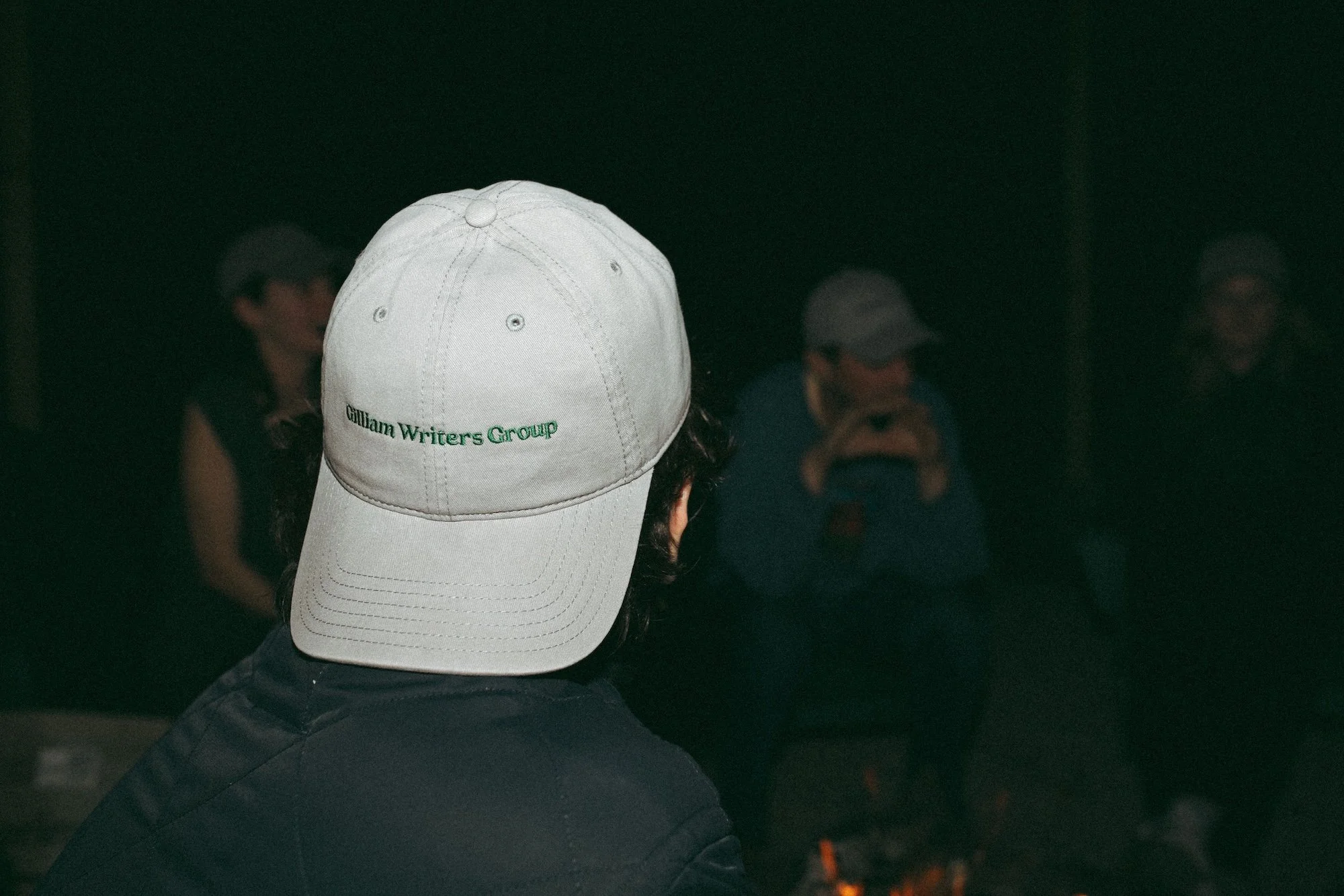 A Gilliam Writers Group cap worn by firelight at the evening gathering.