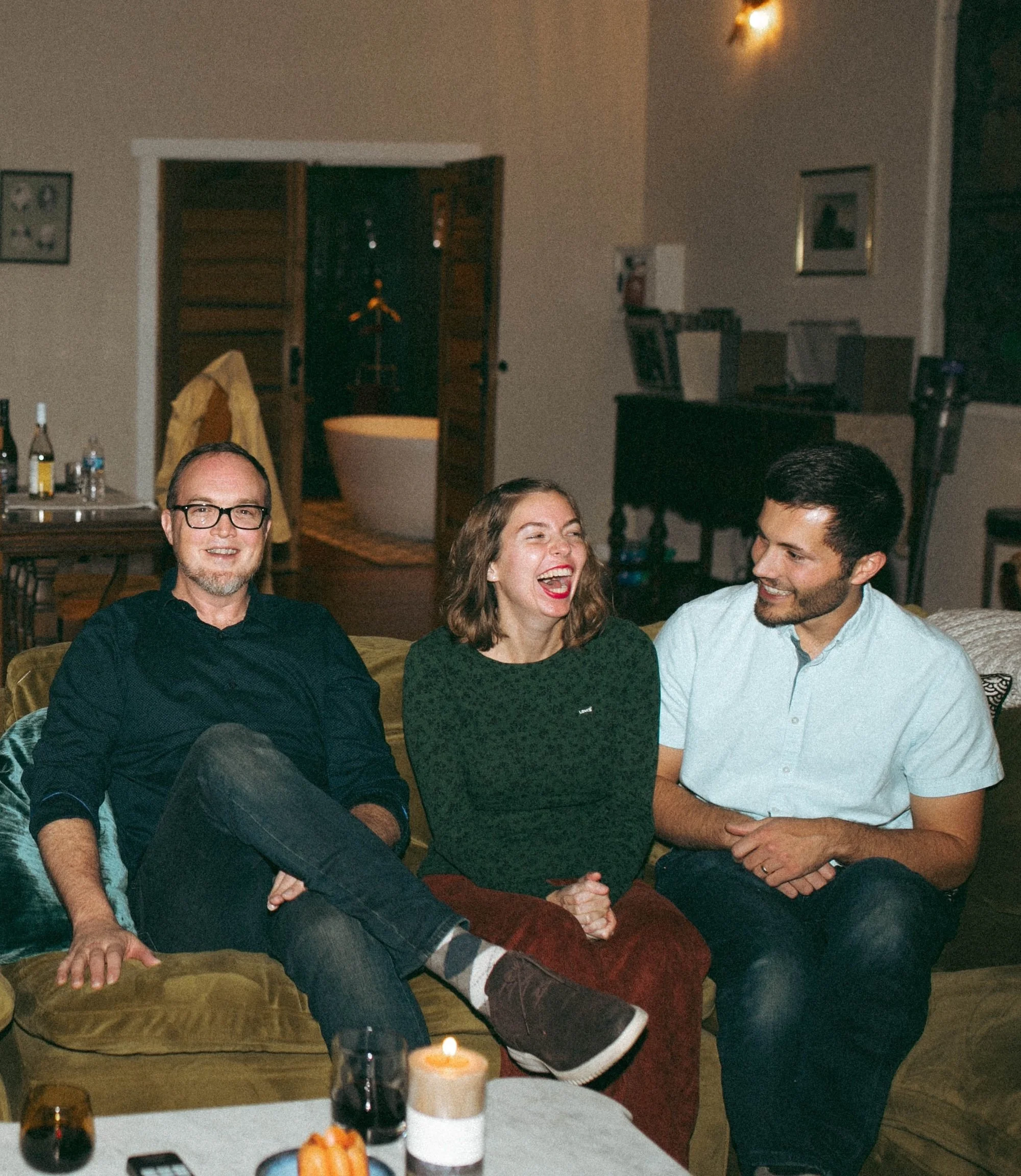 Three Gilliam Writers Group colleagues laughing together on a couch at a company event.