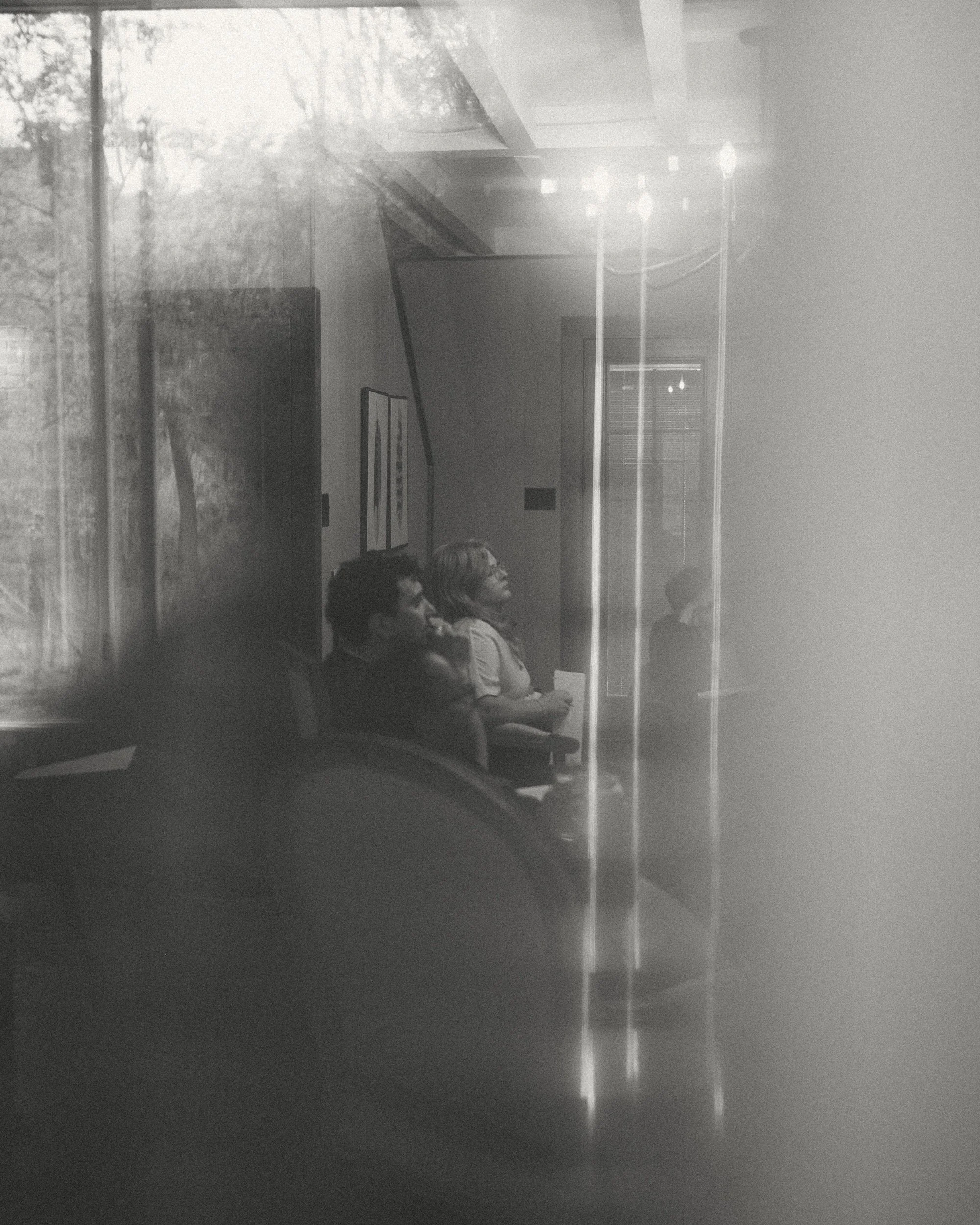 Two writers listening intently, reflected in a window at the retreat.