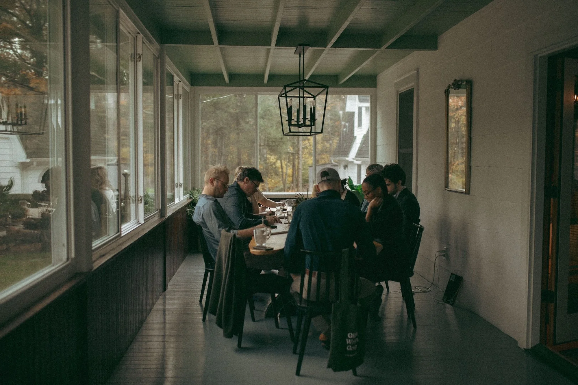 Gilliam Writers Group faculty writing together around a long table in a sunroom.