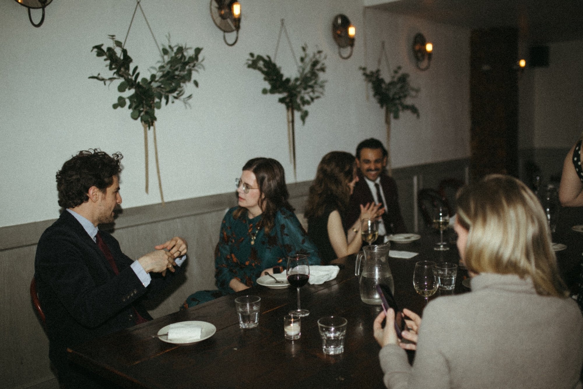 Gilliam Writers Group faculty in conversation around a greenery-draped dinner table.