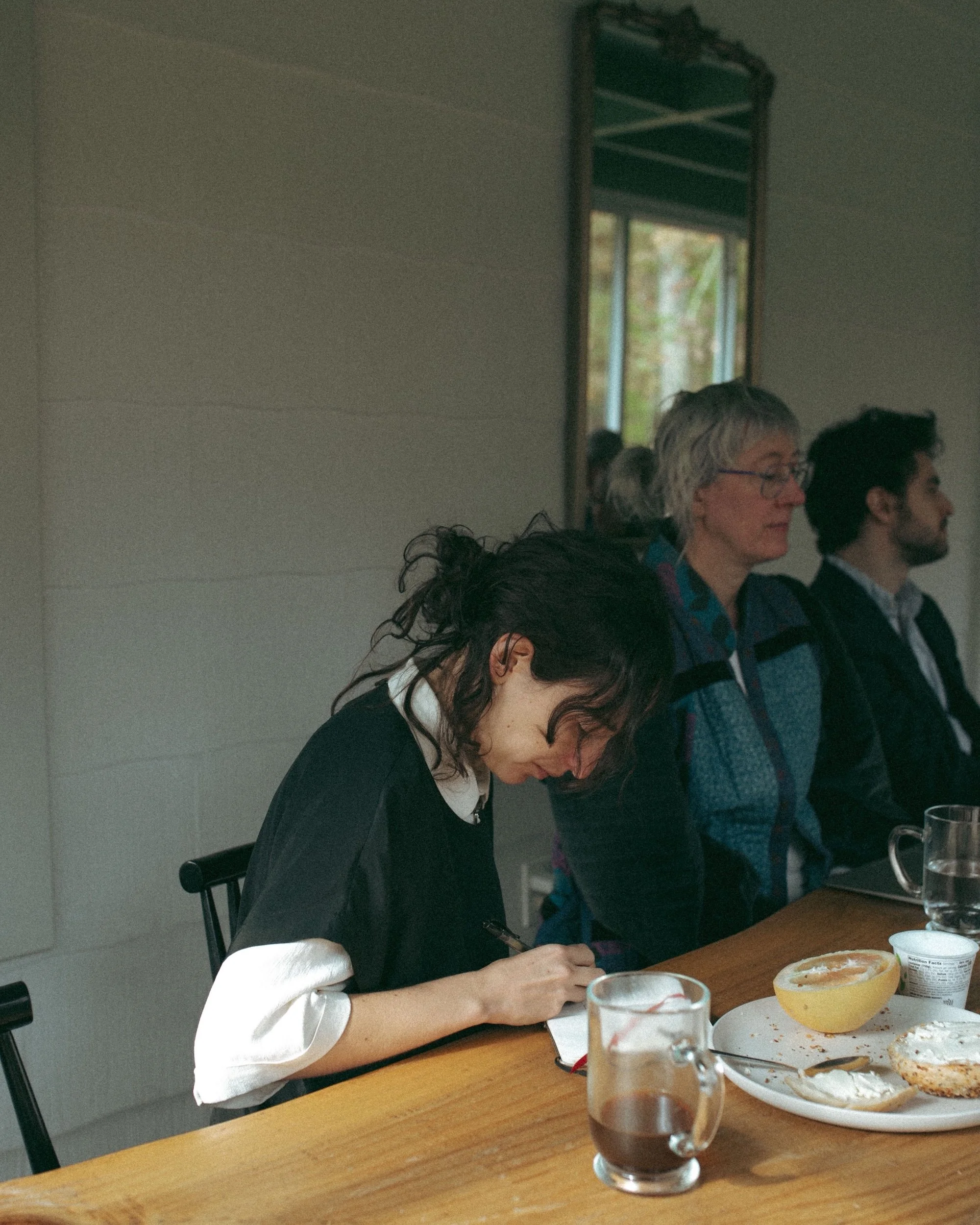 A writer drafting by hand over breakfast during a morning workshop.