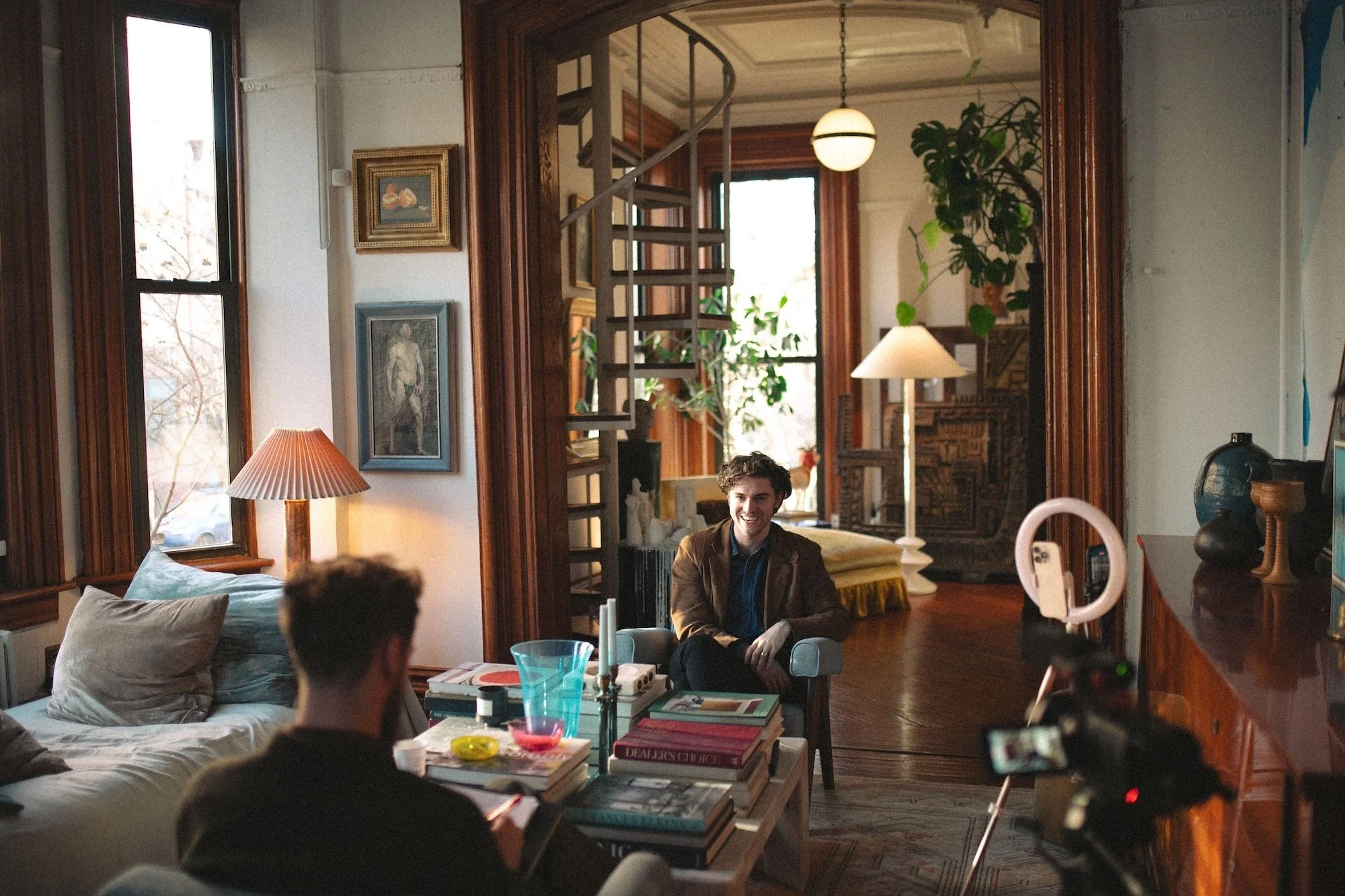 A faculty member being filmed for an interview in a sunlit brownstone.