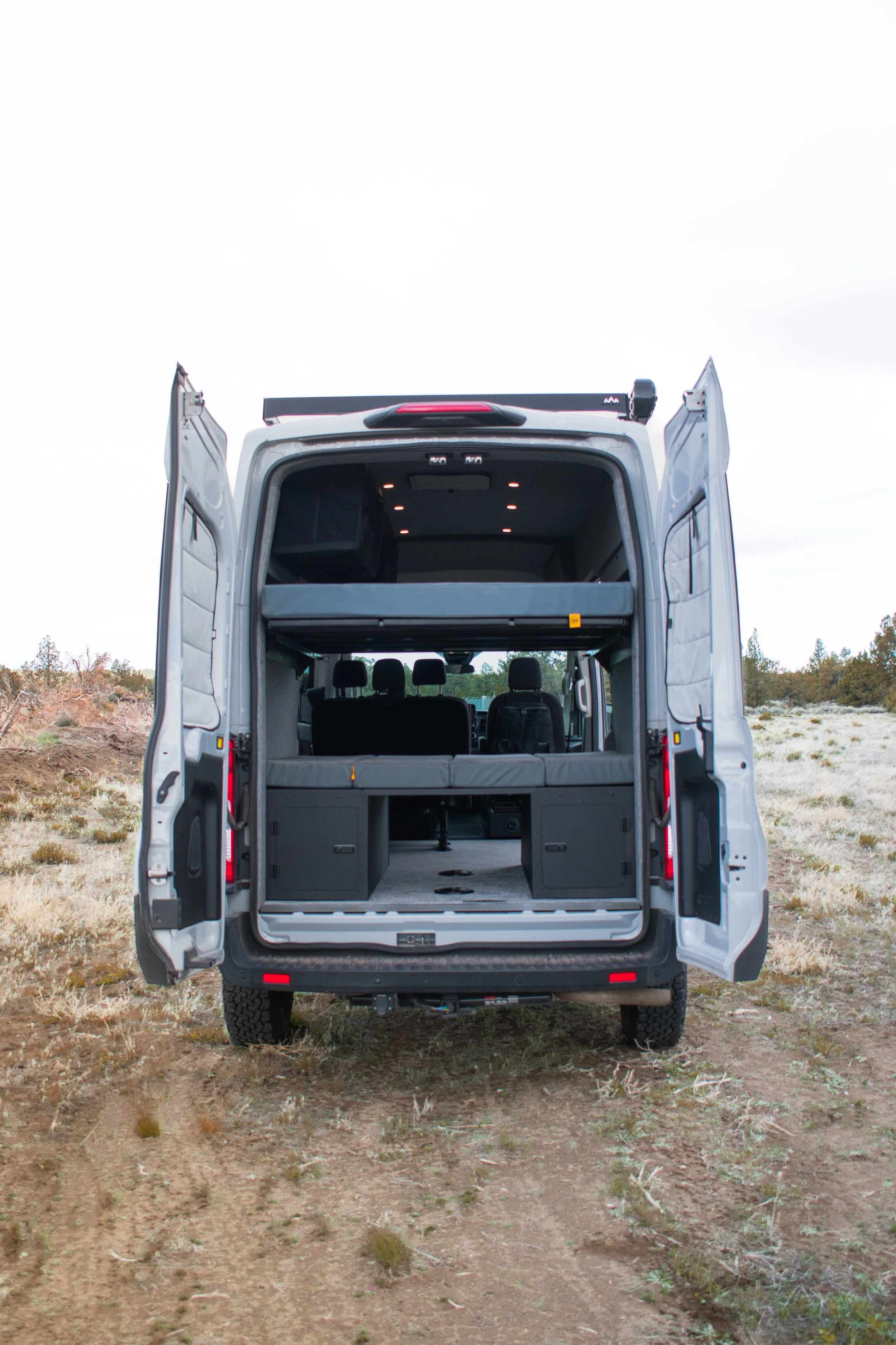 Ford Transit van with rear barn doors for easy access to toys and tools – off-grid camper conversion by Oxbow Vans