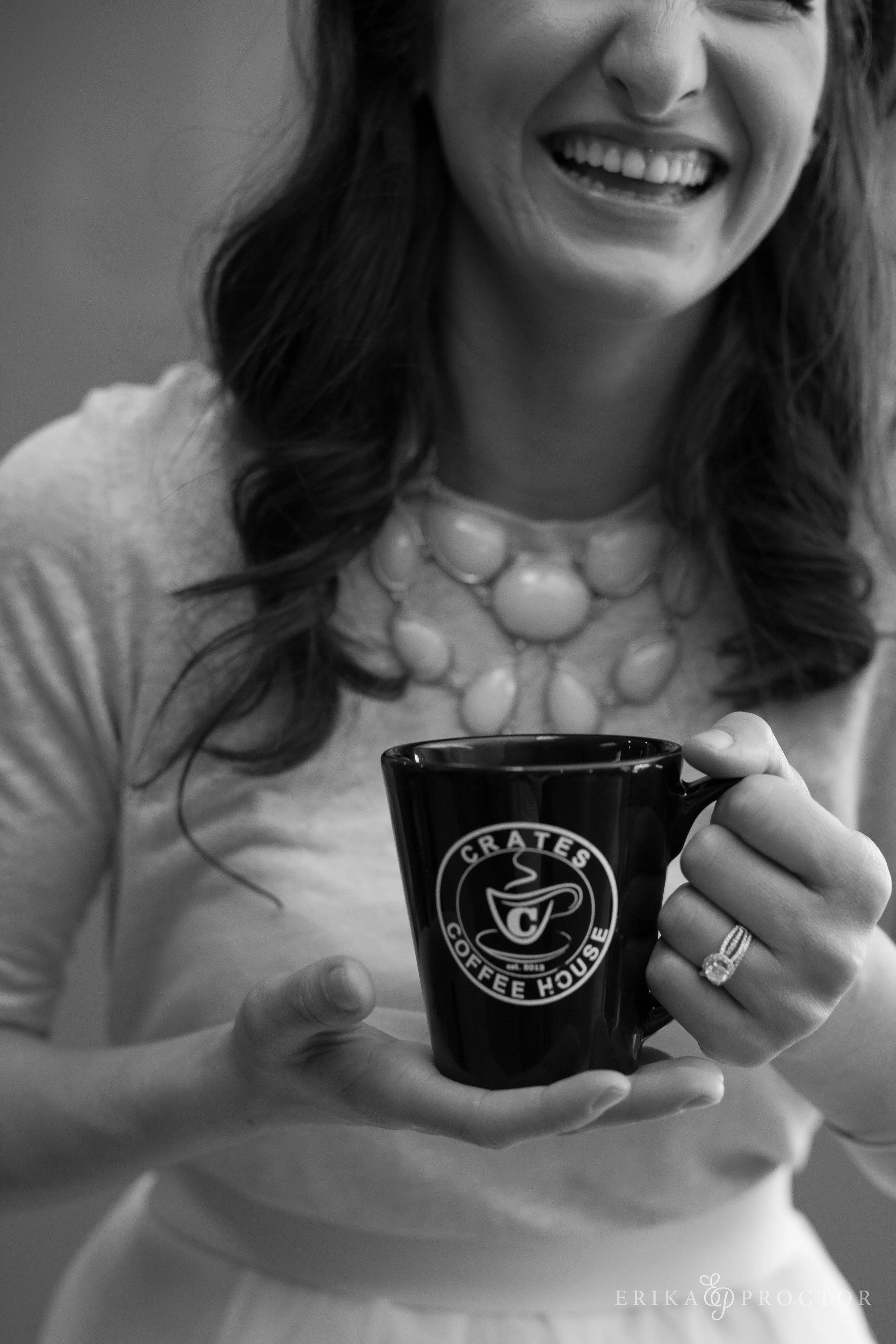 A smiling woman holding a coffee mug labeled 'Crates Coffee House' in black and white.