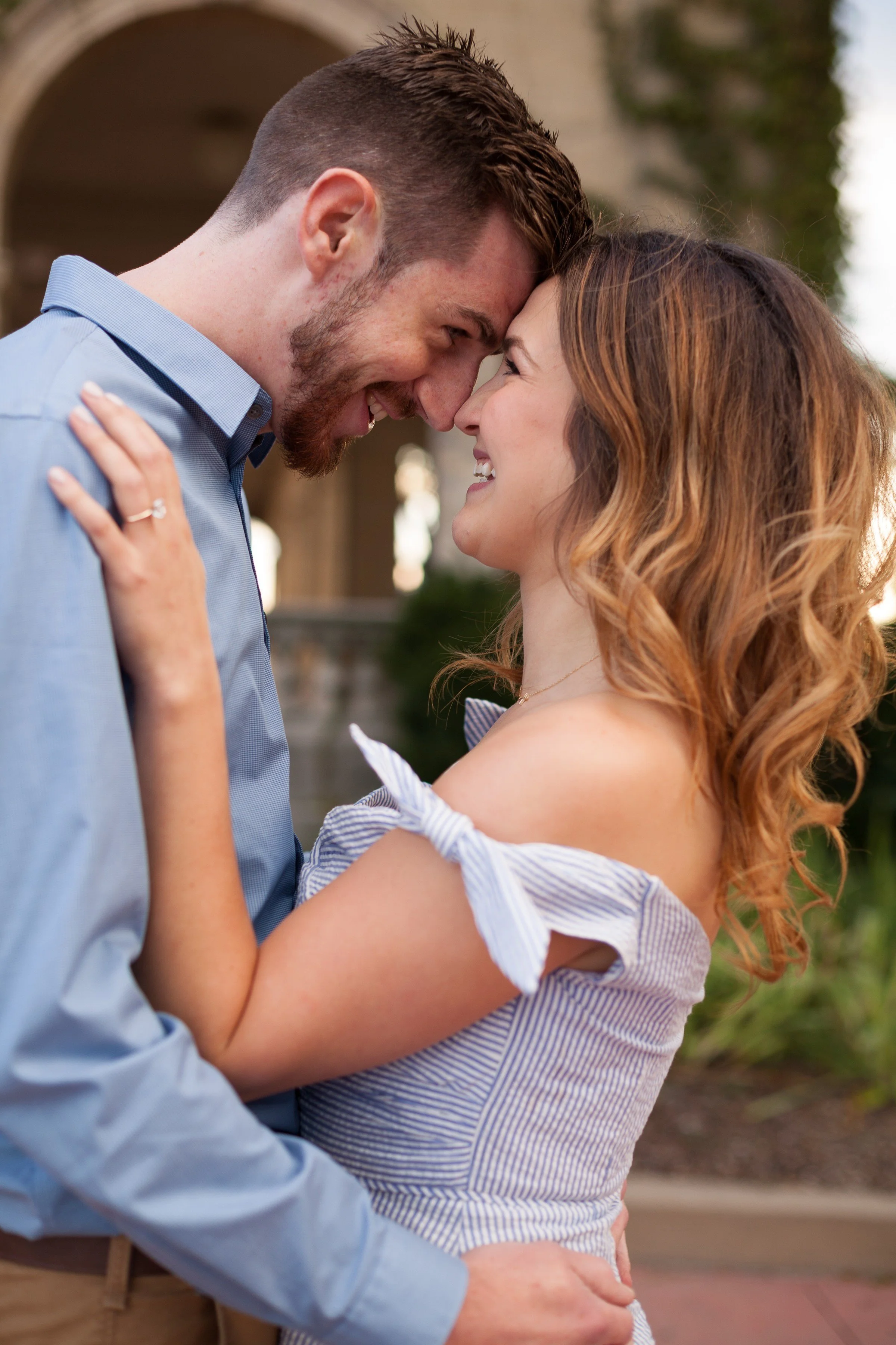 A smiling couple with their foreheads touching, sharing an intimate moment outdoors.