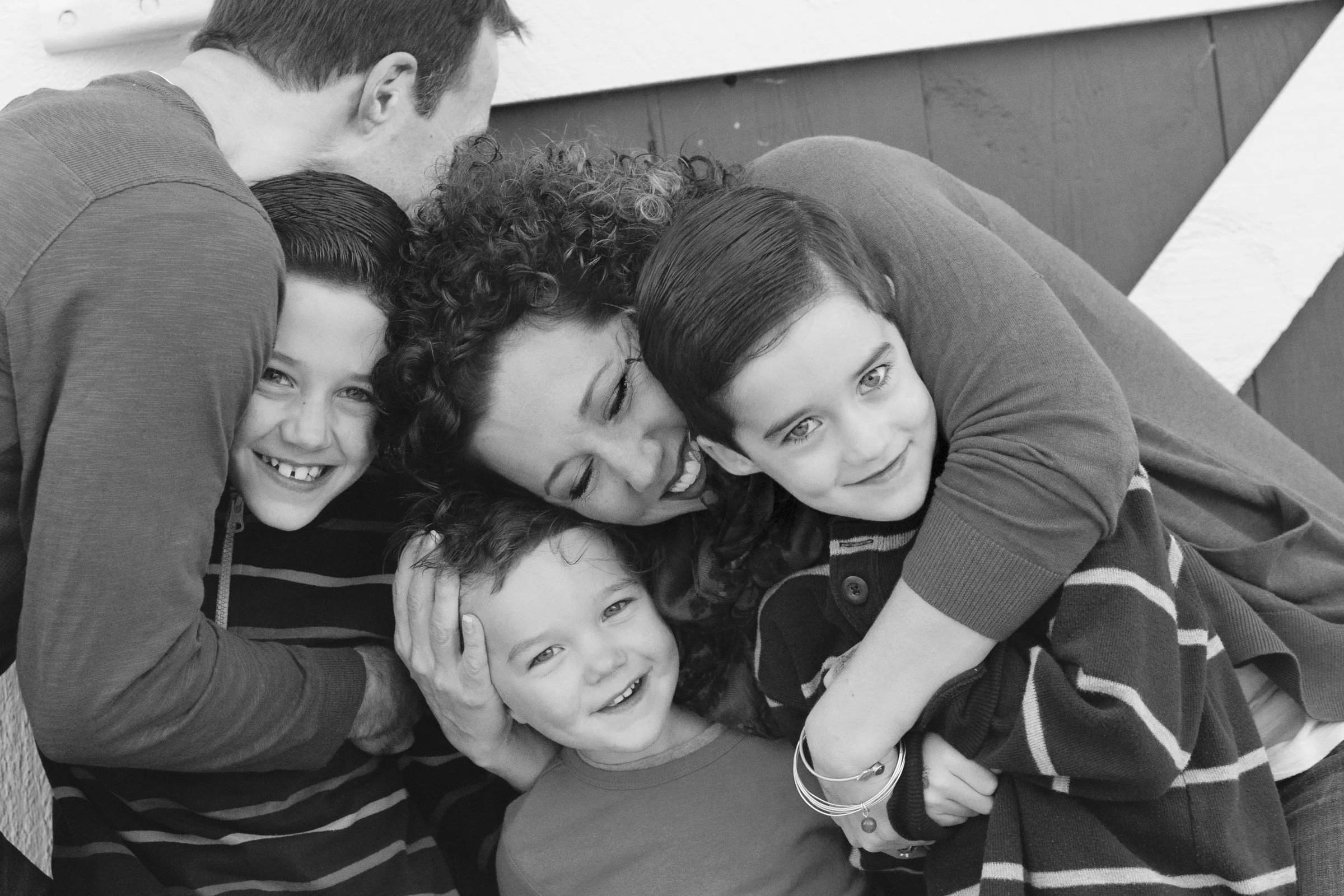 Black and white photo of a woman and four children hugging and smiling.