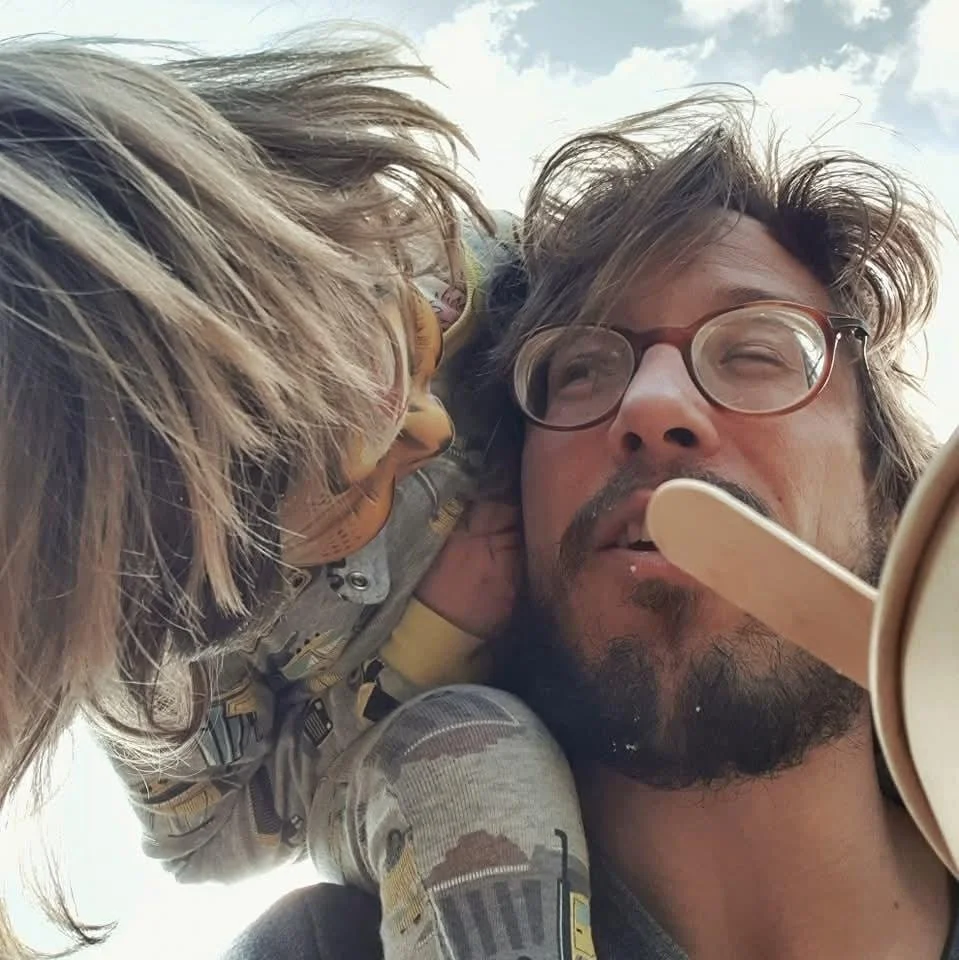 A man with glasses and a beard is holding a Cupcake ice cream and a child with long hair and glasses is close to him, looking at him.
