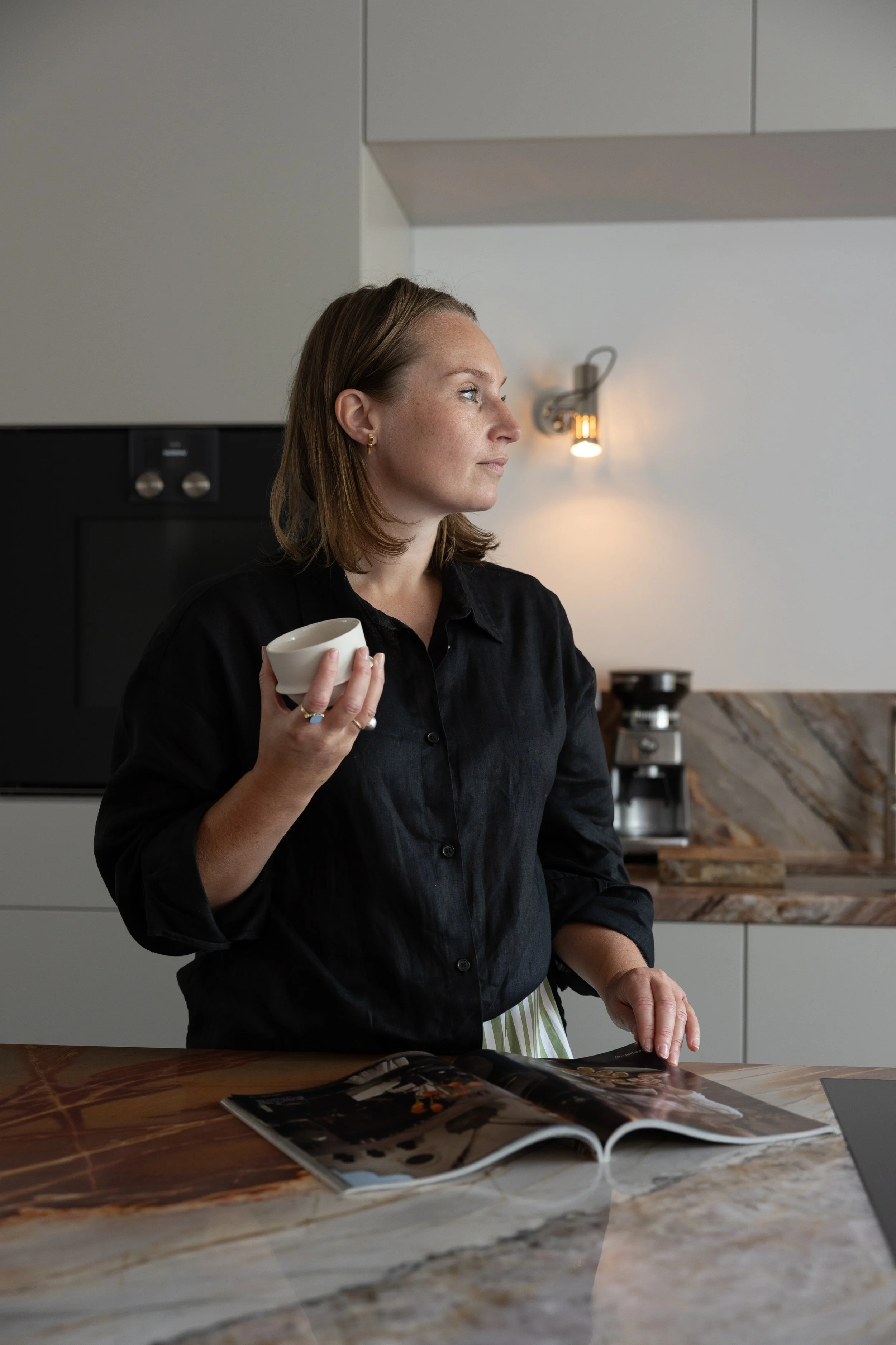 Gisela Draijer, owner of Studio GD. Standing in her latest interior design project, a modern kitchen with natural quartzite countertop. A calm, warm space that feels open yet grounded. Designed for living.
