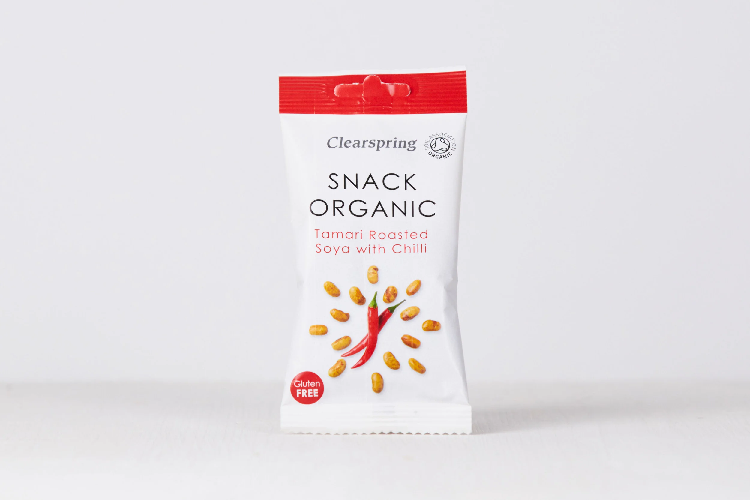 A white snack package with red accents labeled 'Snack Organic Tamari Roasted Soya with Chilli' showing an illustration of red chili and soybeans. The package indicates it is gluten free and is from the brand Clearspring.