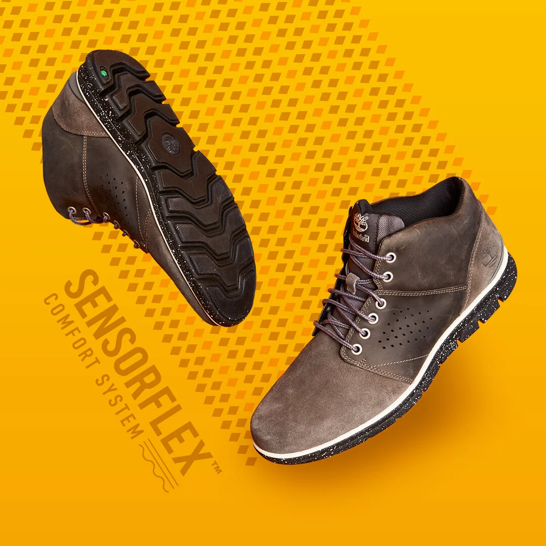 Pair of Timberland Sensusolex comfort system boots on an orange background with Timberland logo and text.