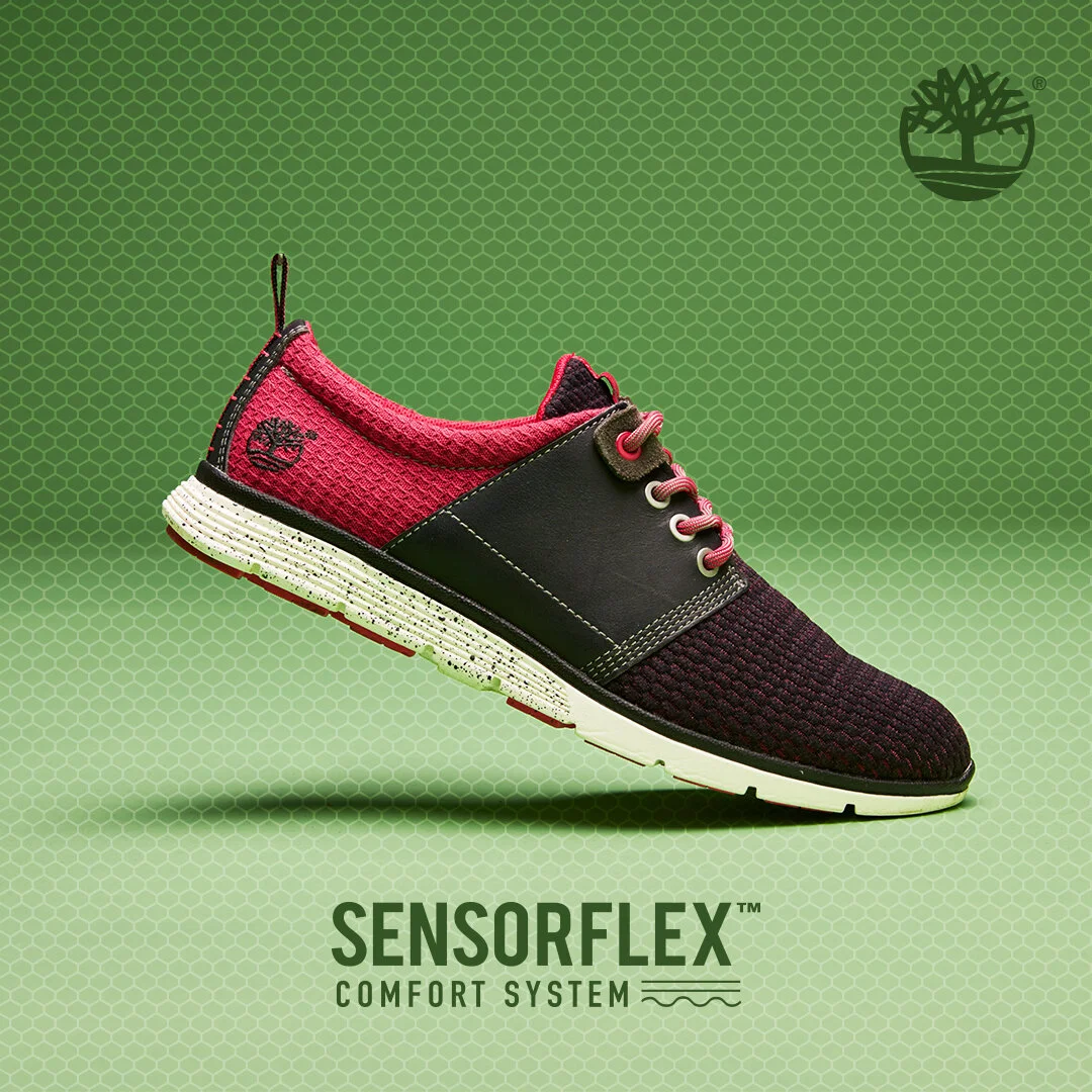 A stylish athletic shoe with a black and pink upper, white sole, and a textured pattern, displayed against a green background with the text 'SENSORFLEX Comfort System'.
