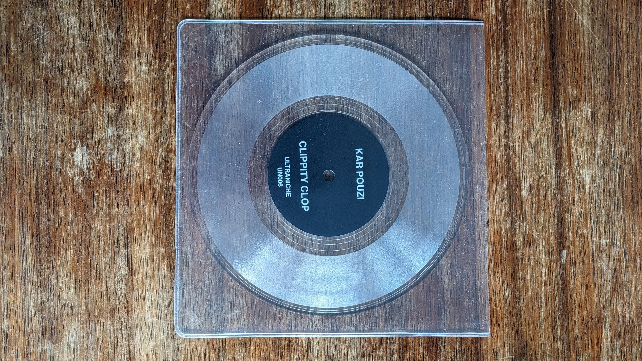 Kar Pouzi clear vinyl on scratched table. label text reads Kar Pouzi Clippity Clop. ultraniche. un006.