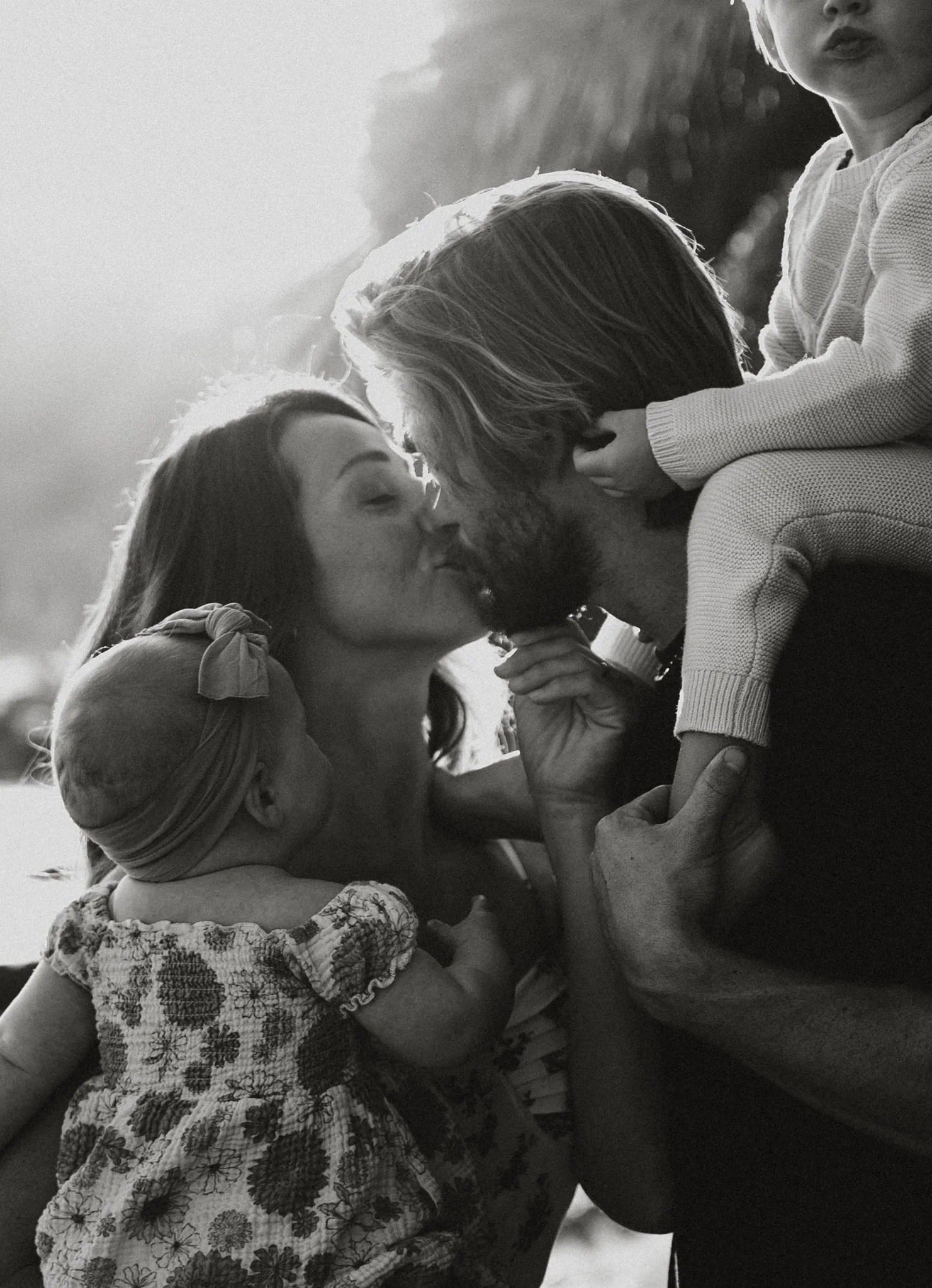 a close up of a couple kissing while they hold their babies 
