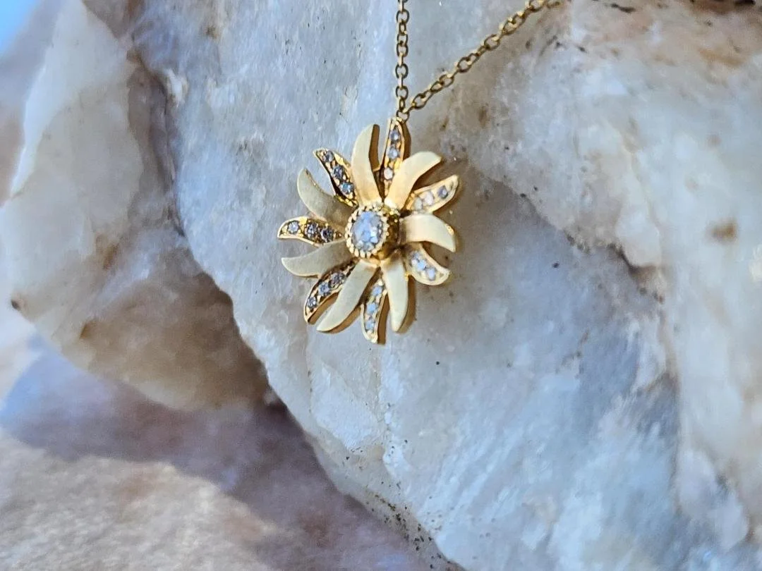 yellow gold diamond flower necklace on white quarts rock and pink velvet