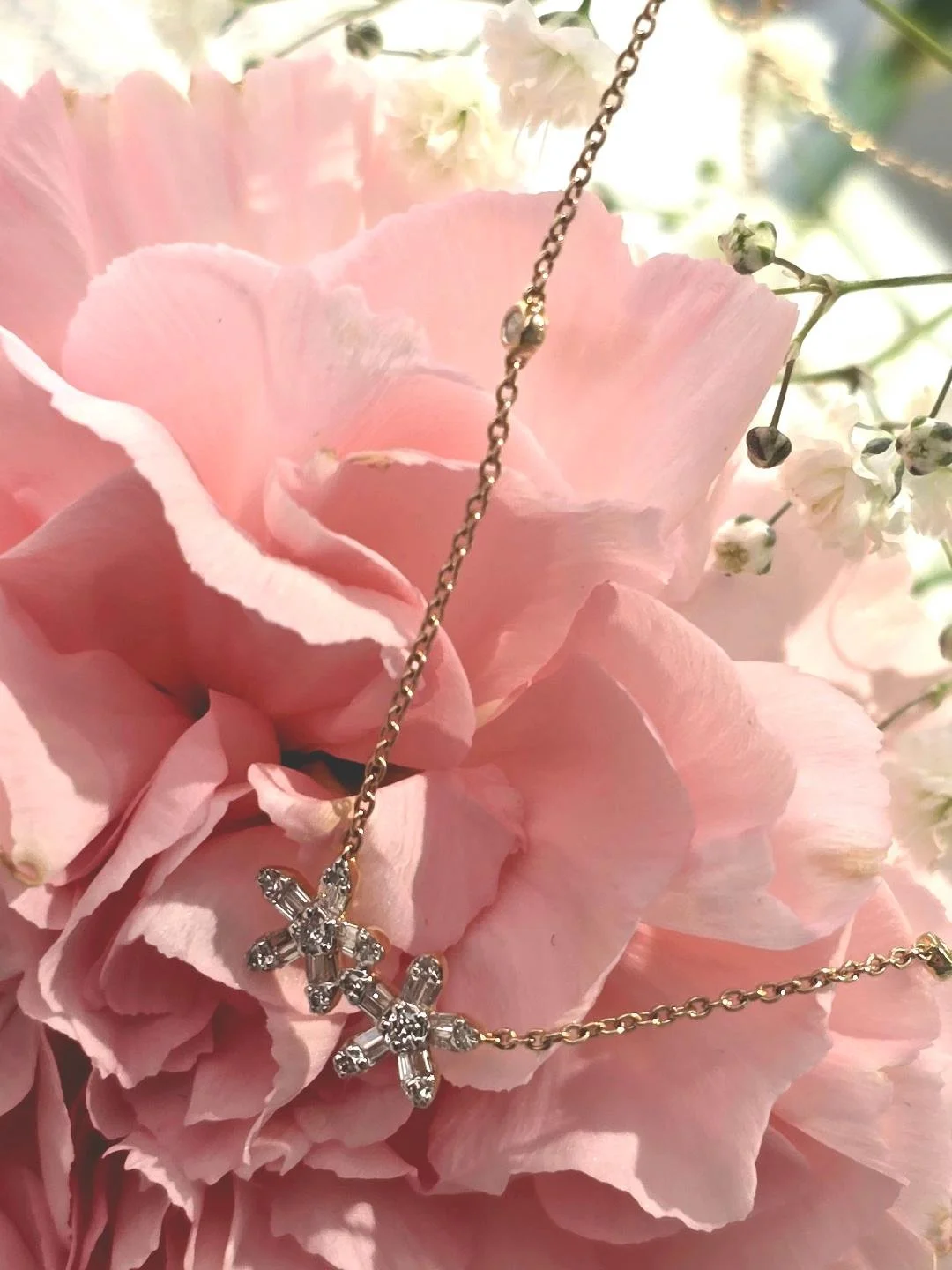 Angled view of yellow gold flower pendant set on pink carnation