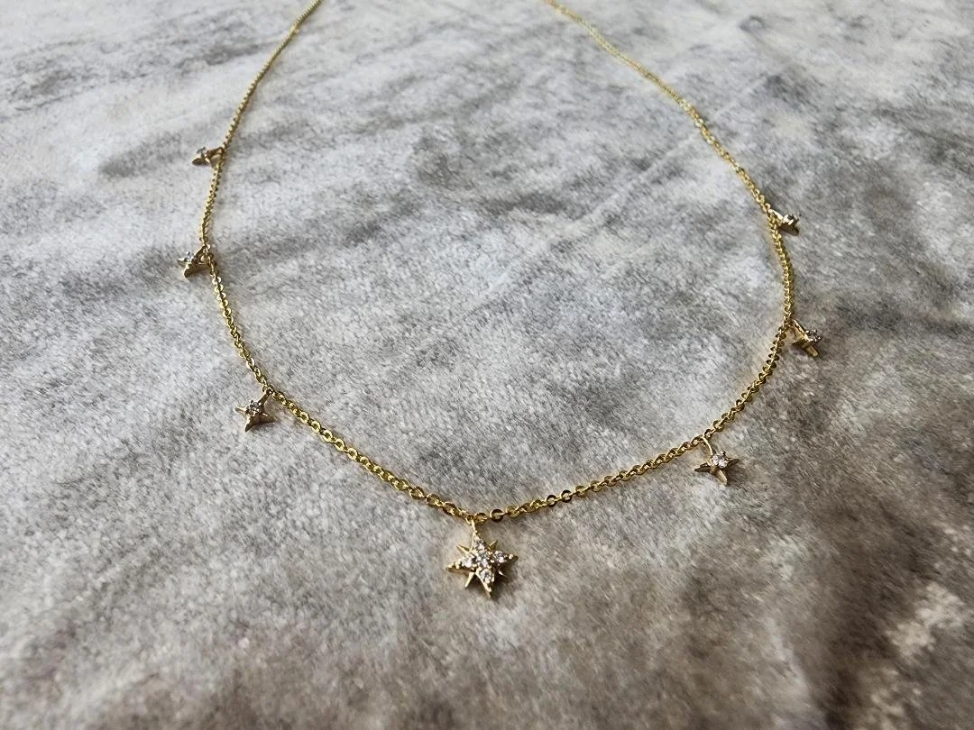 yellow gold diamond star necklace on grey fabric