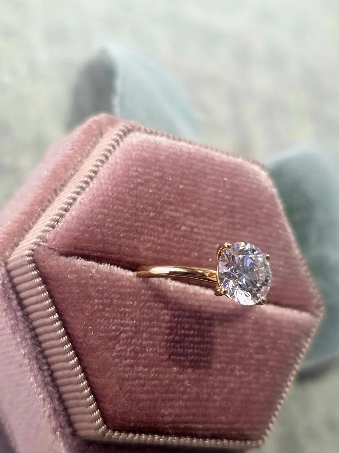 Side view of the yellow gold ring in a pink velvet box with grey velvet background