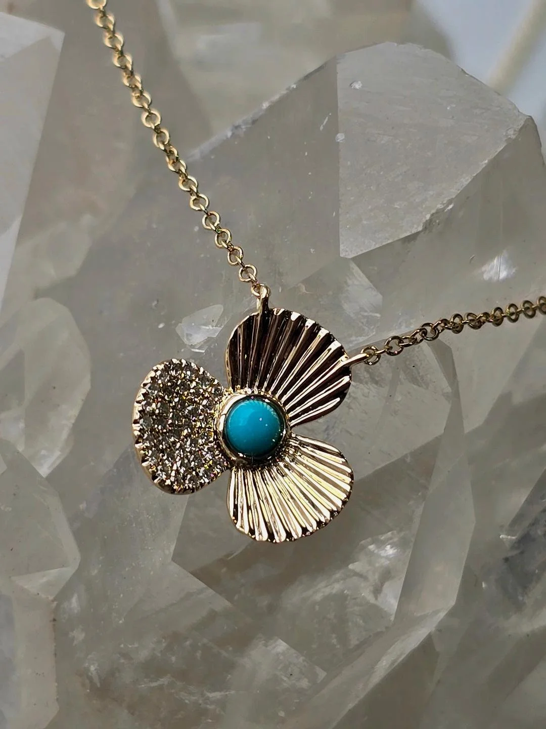 Angled view of a flower turquoise pendant of a crystal background