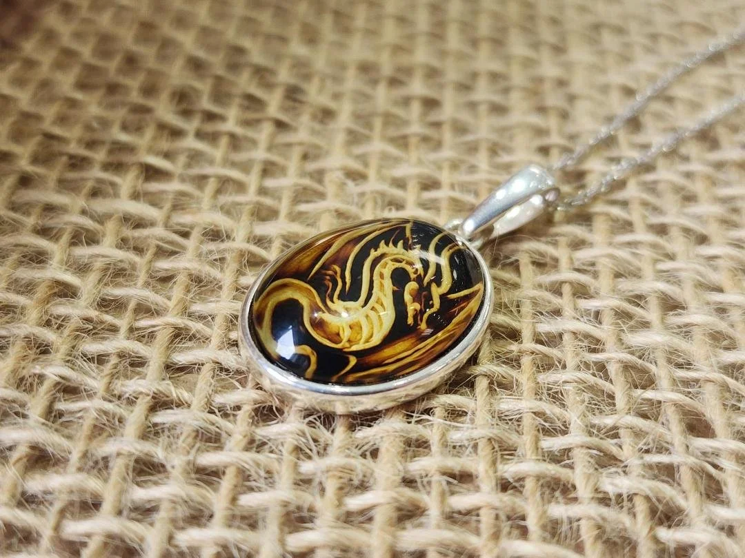 dragon carved amber necklace in sterling silver on a burlap background