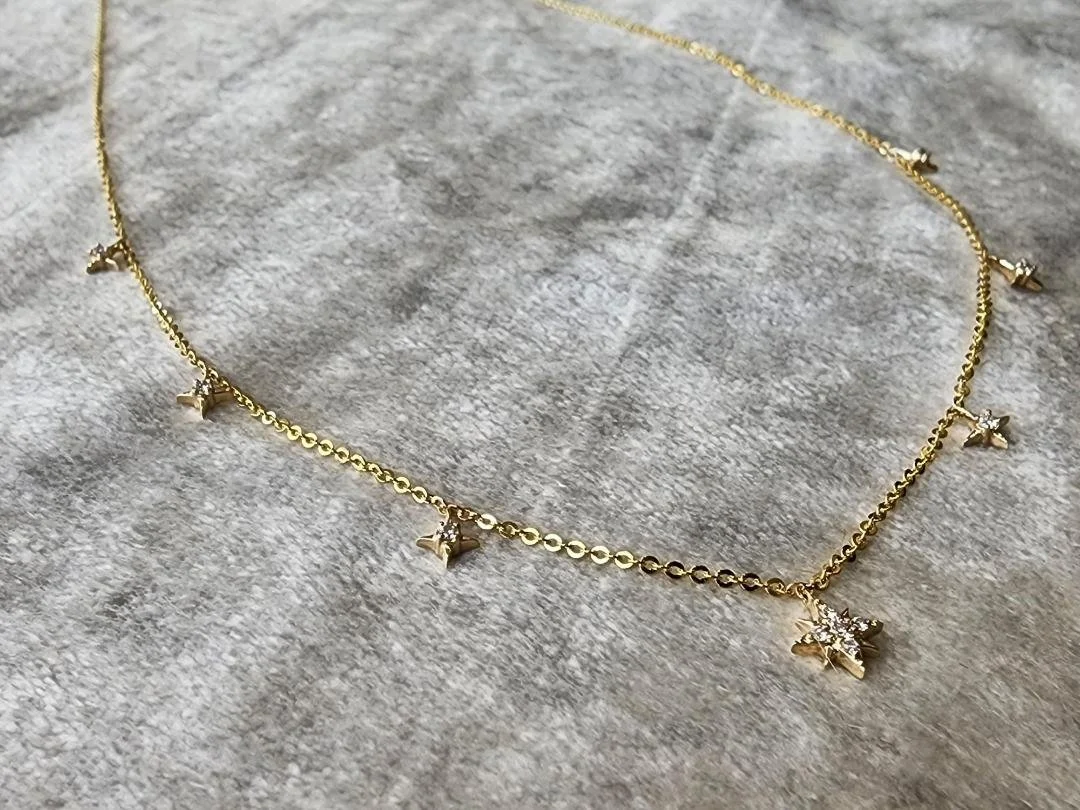 yellow gold diamond star necklace on grey fabric