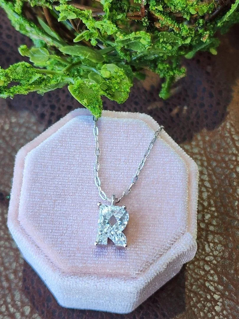 Fancy Cut R lab grown diamond necklace in white gold on a pink box with a green plant and brown back ground