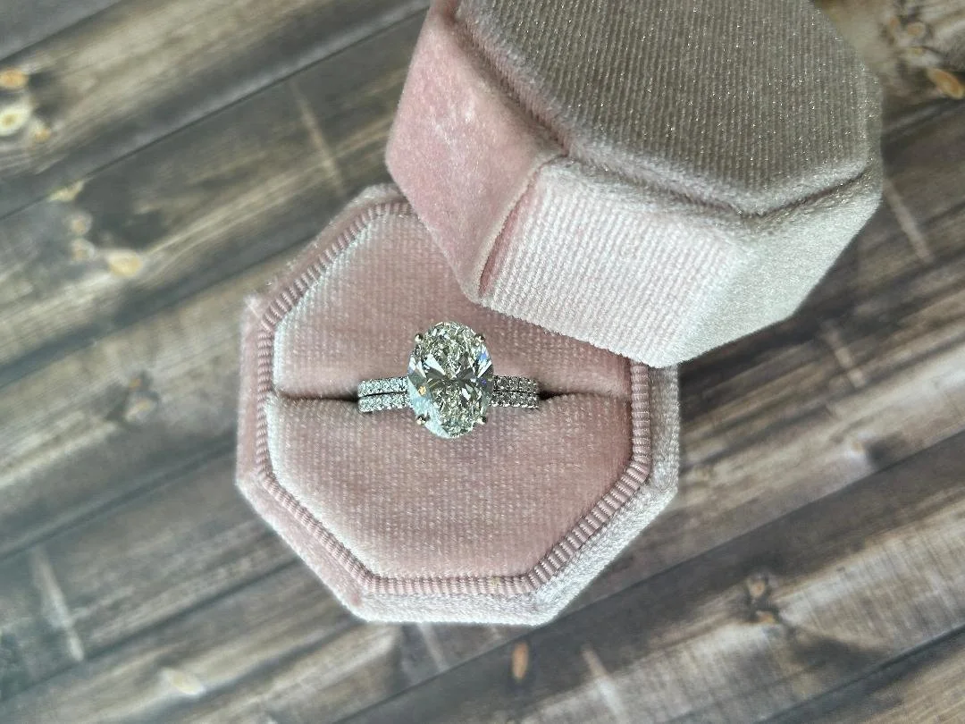 white gold wedding ring set and matching wedding band with diamond accents in pink velvet box and wood in background