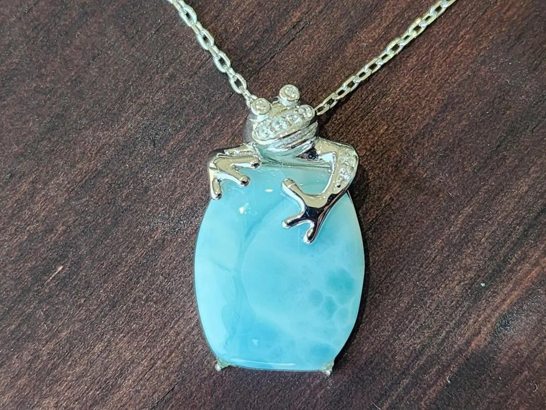blue Larimar with a necklace with frog on chain on dark wood background