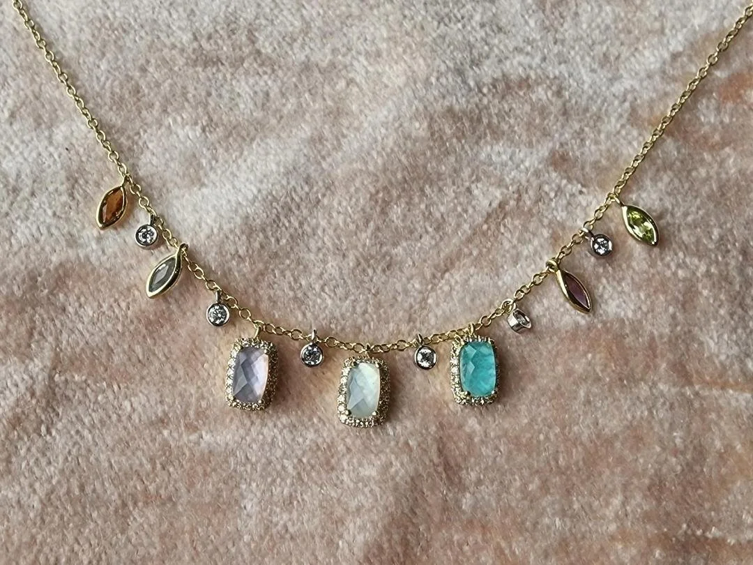 Multi colored pastel necklace in 14k yellow gold on pink velvet background