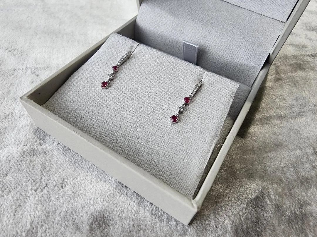 white gold ruby and diamond dangle earrings in grey box