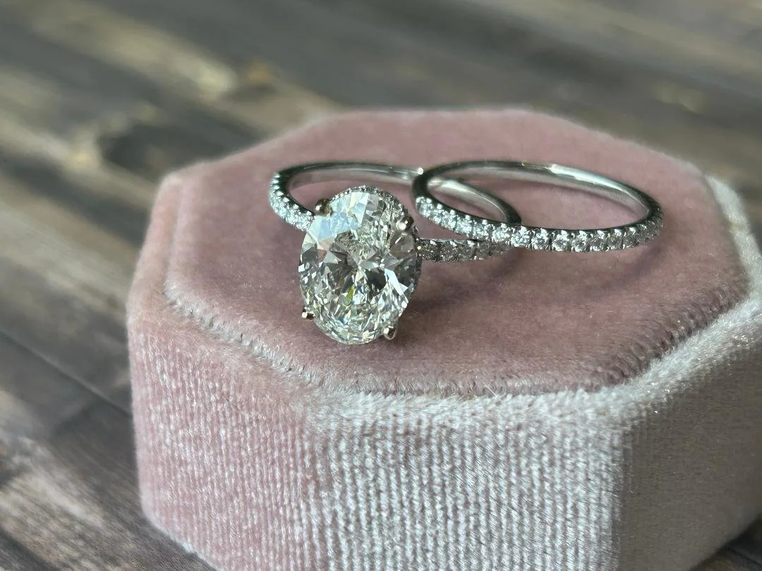 white gold wedding ring set and matching wedding band with diamond accents on pink velvet box and wood in background