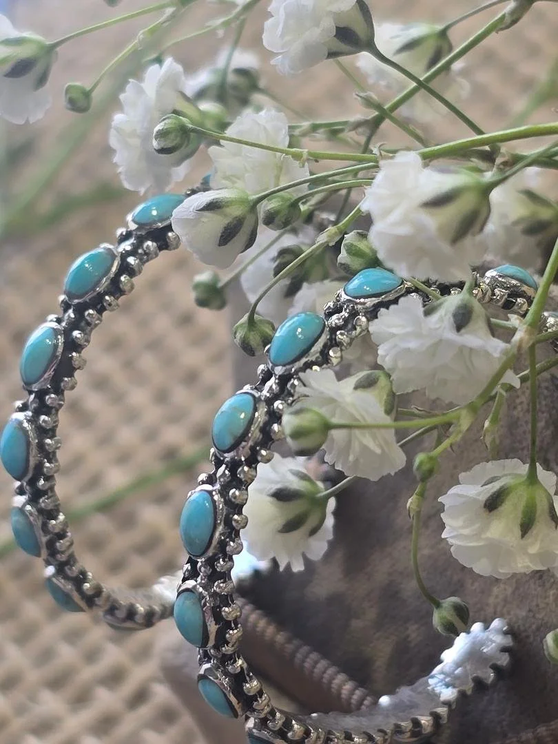 Side view of oval turquoise hoops in brown box with white flowers