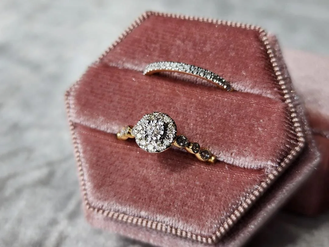 One yellow gold wedding ring set with round diamond halo engagement ring and straight diamond wedding band in pink box on grey fabric