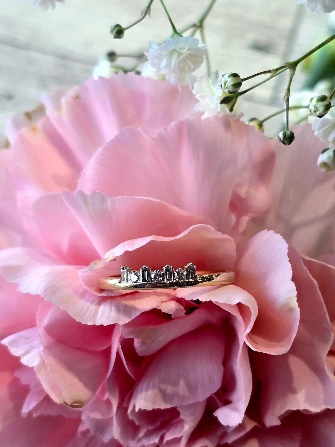 Front view of yellow gold band set in a pink carnation with small white flower at the top