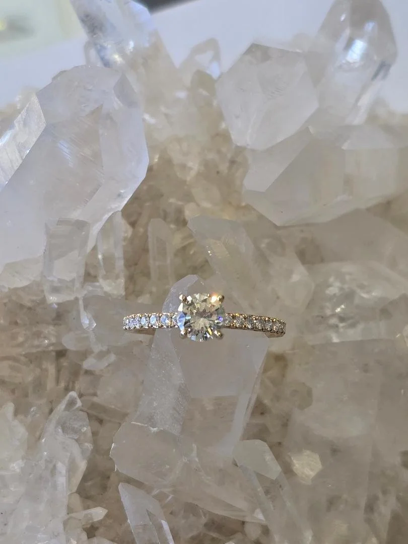 Front view of yellow gold engagement ring set on top of a white crystal