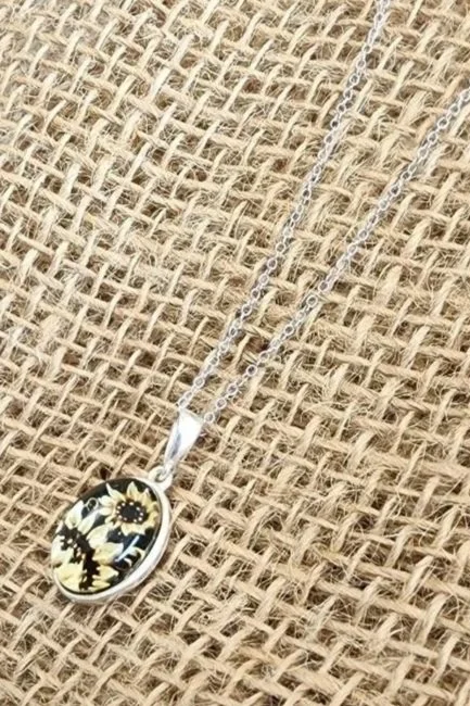 sterling silver oval amber with two carved sunflowers on a burlap background