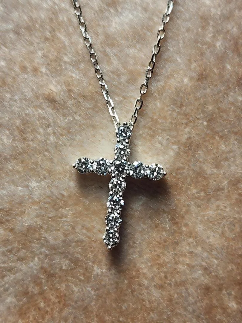 Sterling silver lab grown diamond cross necklace on chain on pink velvet background