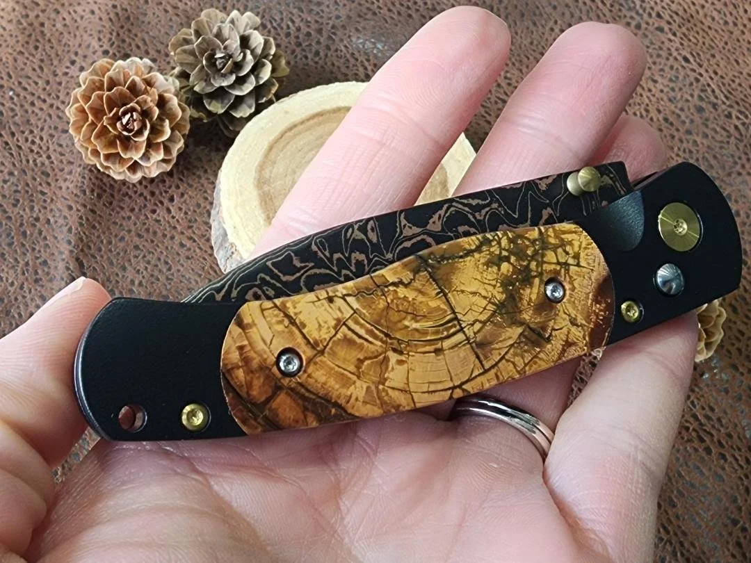 hand holding copper and brass Damascus knife with Mammoth ivory inlay