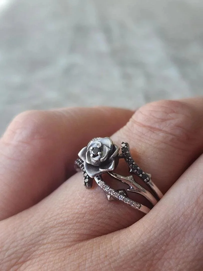 estate sterling silver rose ring with white and black diamonds on women's hand with grey backround